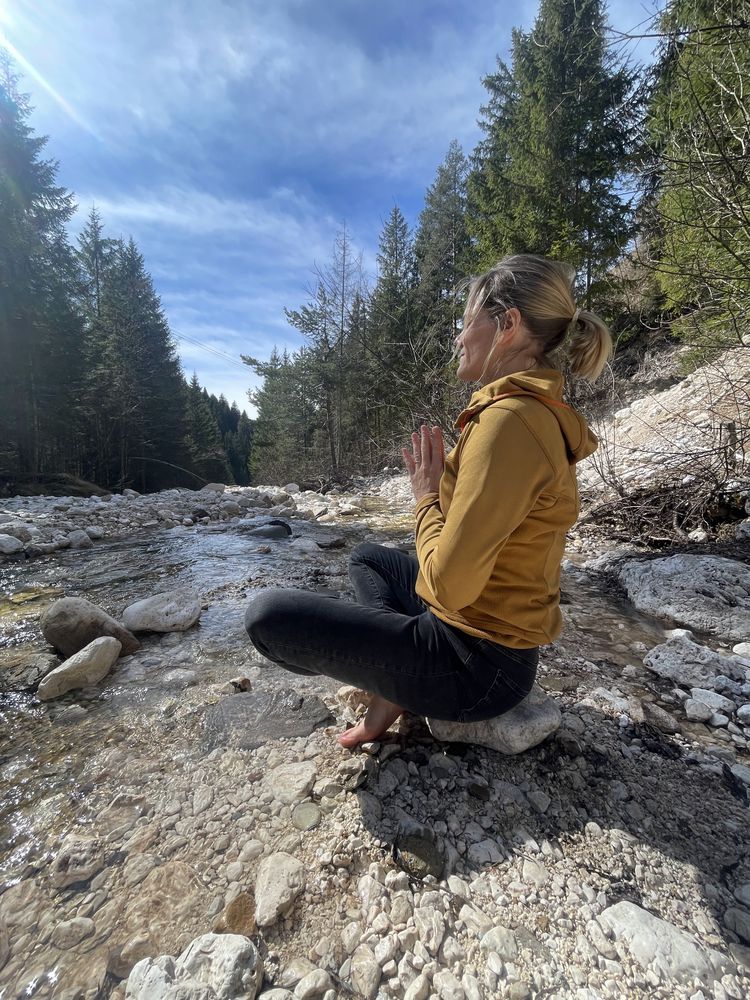 Mirja Stern in Meditationshaltung an einem Gebirgsbach